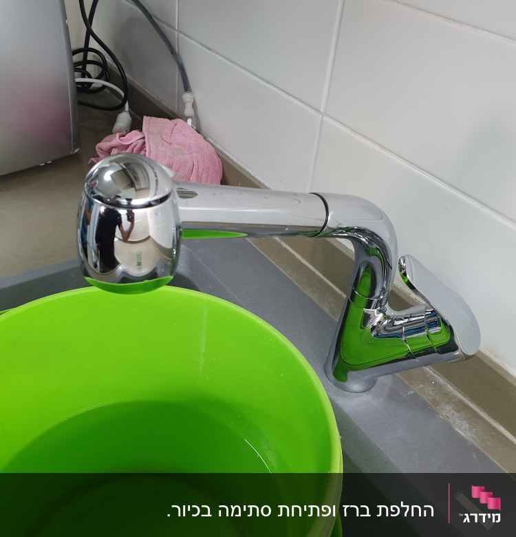 ברז מטבח עם דלי ירוק מלא במים